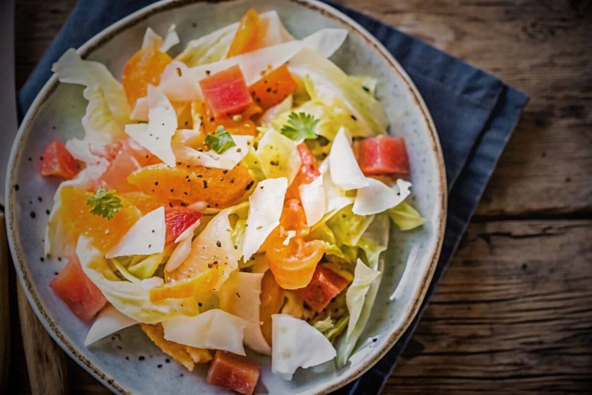 salade d'endives fraîche avec pommes, roquefort et noix sur une table noire, idéale pour un repas léger et savoureux.