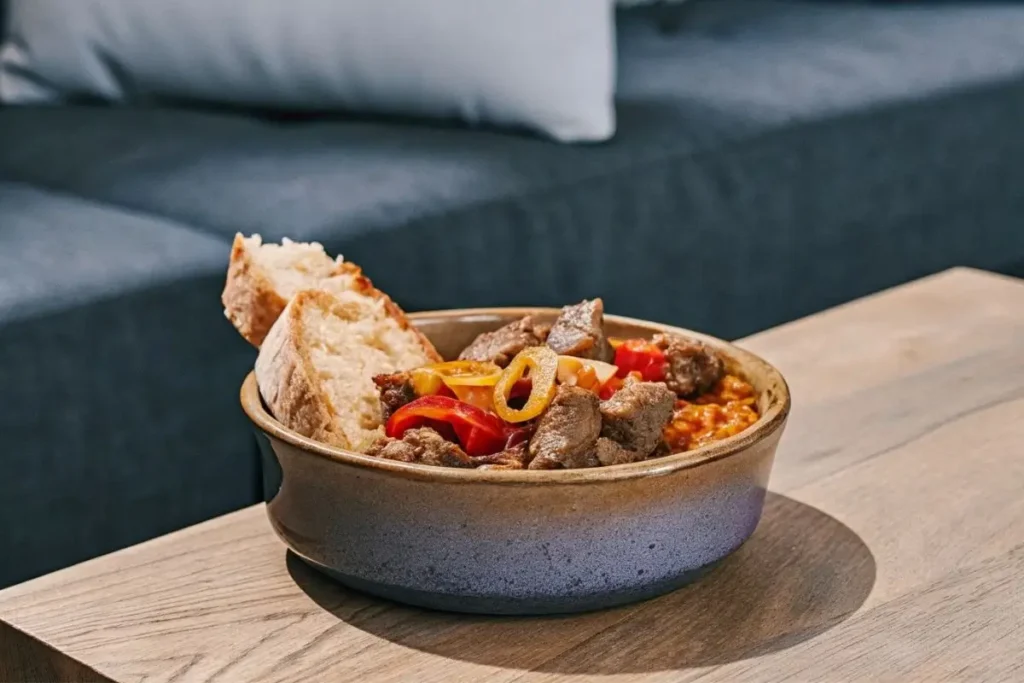 ne délicieuse portion d'axoa de veau dans un bol en céramique rustique, avec du veau tendre, des légumes colorés et une pincée de piment d'Espelette, accompagnée de riz chaud.