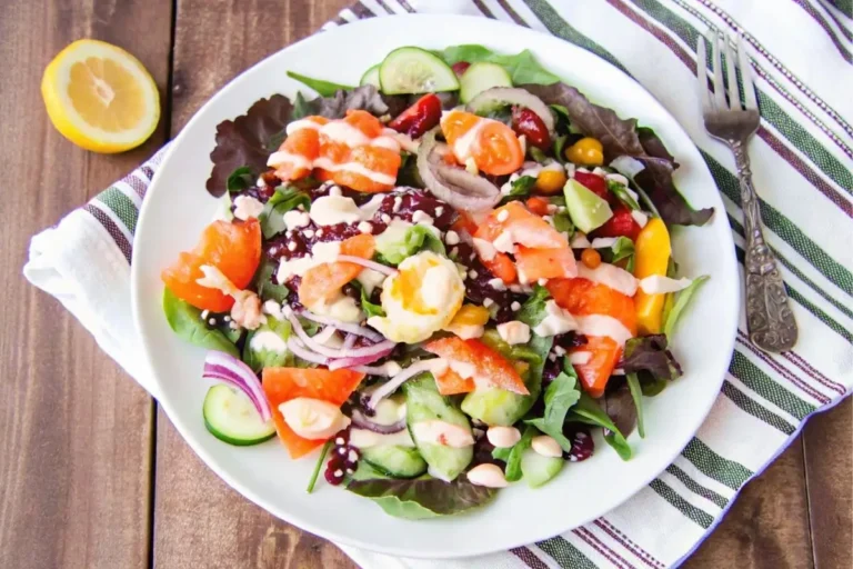Salade élégante composée de fines tranches de saumon fumé disposées sur un lit de mesclun, garnie d'avocat, de tranches de radis et d'un filet de vinaigrette au citron, servie dans un bol blanc avec une fourchette sur le côté.