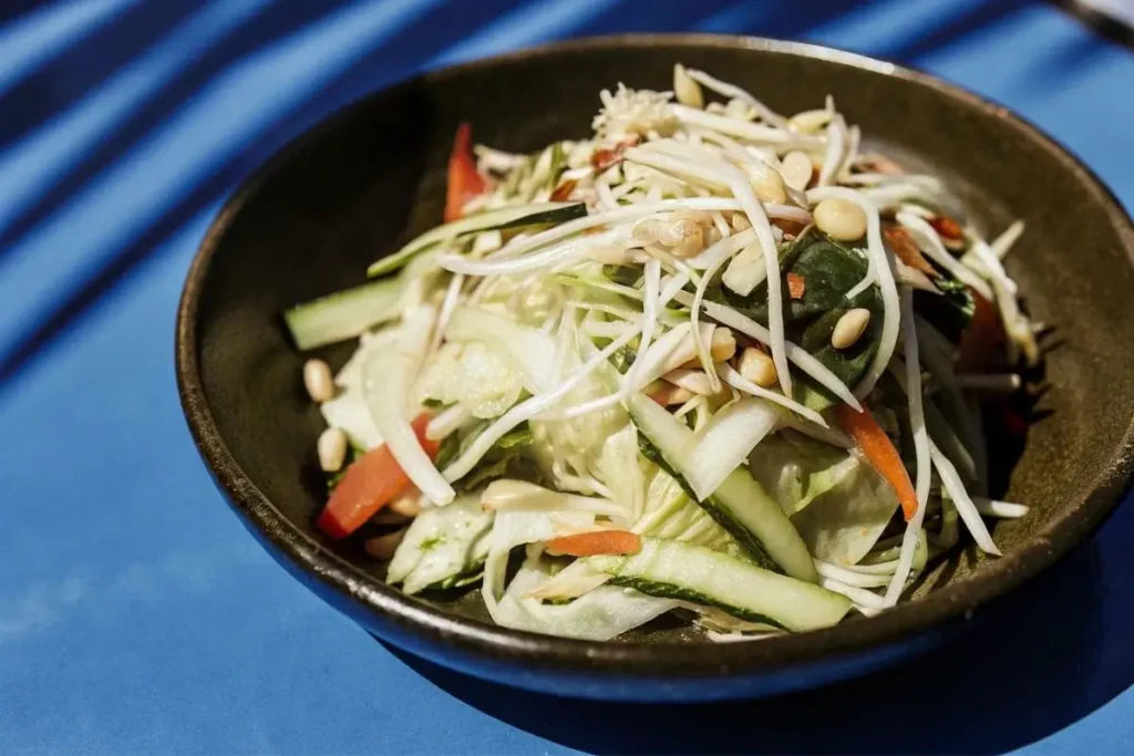 Salade thaï élégante avec légumes frais, herbes aromatiques, et protéines grillées, servie dans un grand bol.