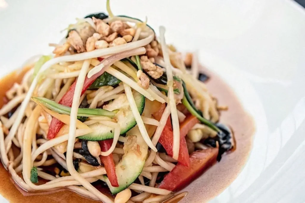 Salade thaï servie dans des bols individuels avec des cacahuètes grillées et des herbes fraîches.