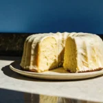 Gâteau citron yaourt vegan, sans œufs ni lactose, décoré de fruits frais et de sucre glace.