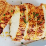 Blanc de poulet doré et juteux sorti du four avec des herbes et épices.