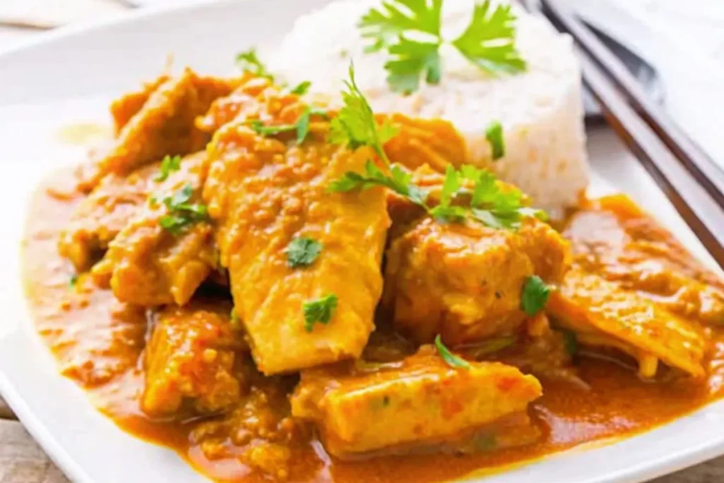 Curry de poisson au lait de coco servi avec du riz blanc, garniture de coriandre et piment frais.